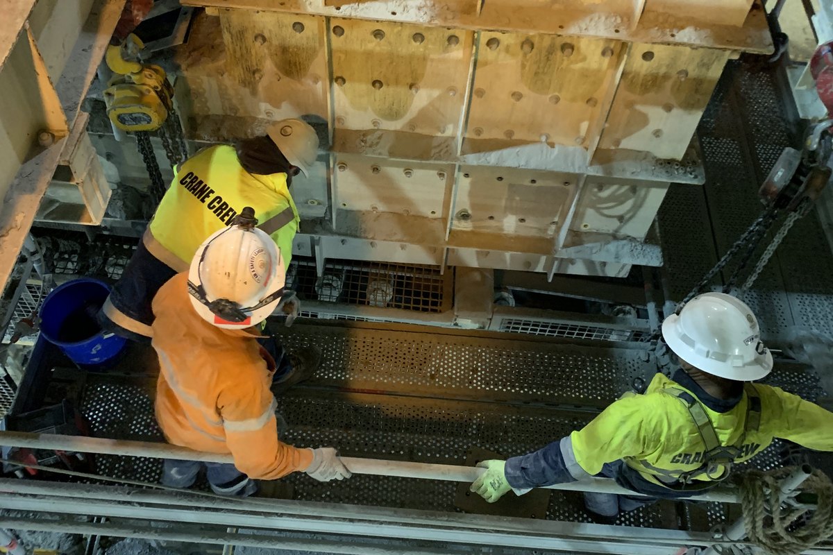 A crane crew rigging a crusher component on chain blocks